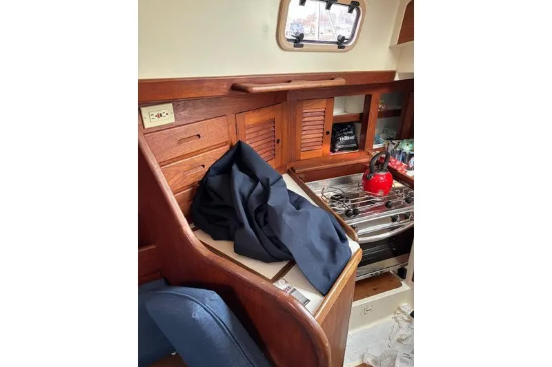 Slide: The Image of Interior of 1988 Tartan 31 sloop with wooden cabinetry and red kettle on stove. - 34