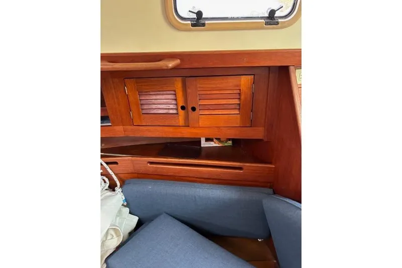Slide: The Image of Interior of 1988 Tartan 31 Cutter Rigged Masthead Sloop with wooden cabinetry and blue cushions. - 43