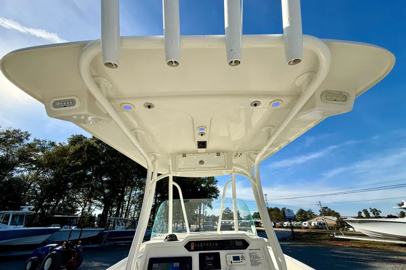 Slide: The Image of 2016 Sailfish 240 CC boat console with T-top and rod holders under clear blue sky. - 49