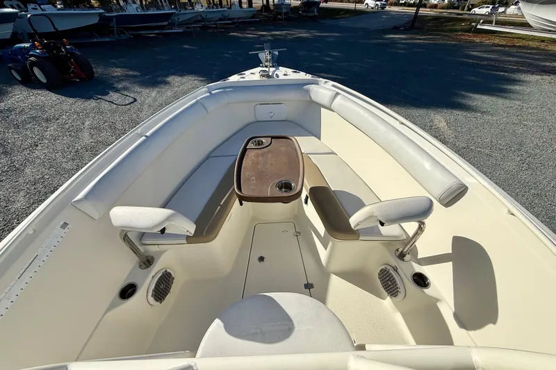 Slide: The Image of 2016 Sailfish 240 CC boat interior with seating and table, parked on gravel. - 55