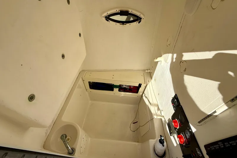 Slide: The Image of Interior view of a 2016 Sailfish 240 CC boat, featuring control panel and storage area. - 58