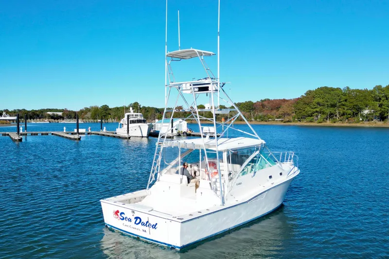 Slide: The Image of 1996 Cabo 35 boat on serene water near a dock, clear blue sky. - 1