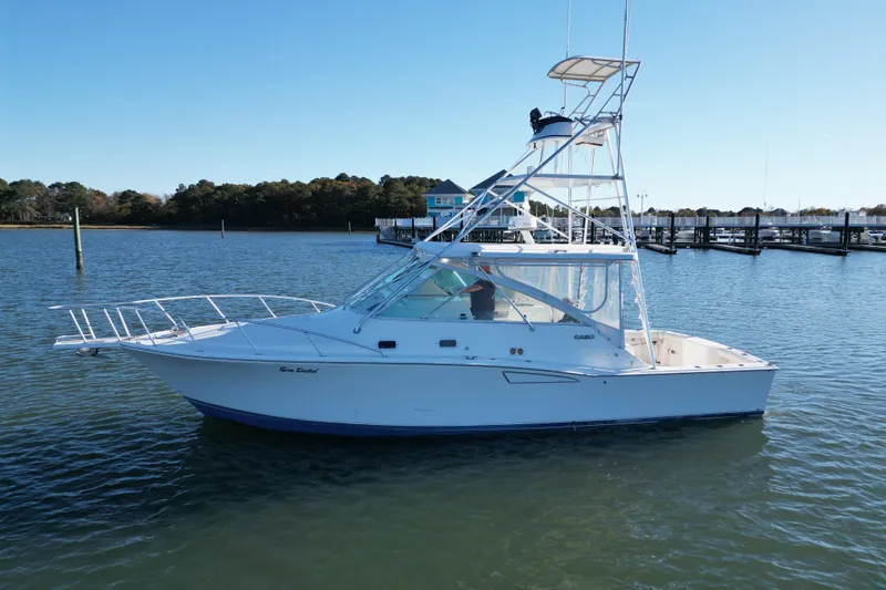 Slide: The Image of 1996 Cabo 35 boat on calm water near a marina, clear sky background. - 3