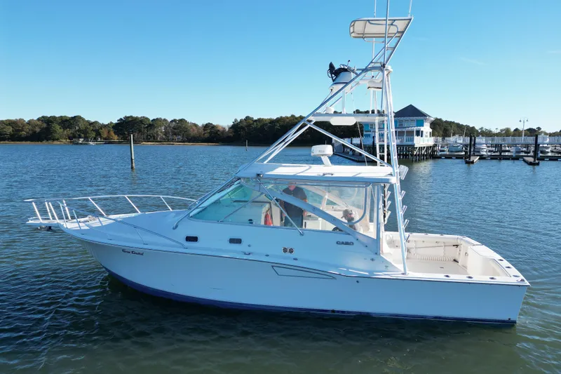 Slide: The Image of 1996 Cabo 35 boat on calm water near a marina, clear blue sky. - 4