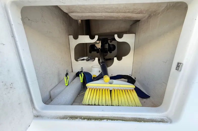 Slide: The Image of Open storage compartment on a 1996 Cabo 35 boat, containing a bucket and fishing gear. - 51