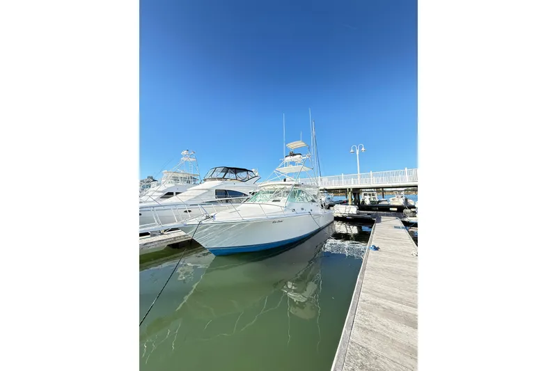 Slide: The Image of 1996 Cabo 35 boat docked at marina, clear sky, "Sea Dated" on stern. - 69