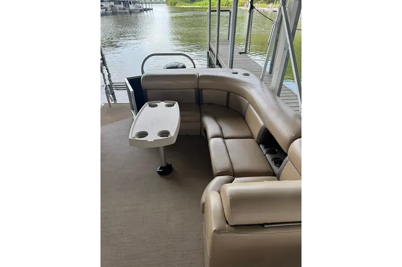 Slide: The Image of 2019 Harris CX 230 pontoon boat interior with beige seating and table by the water. - 6