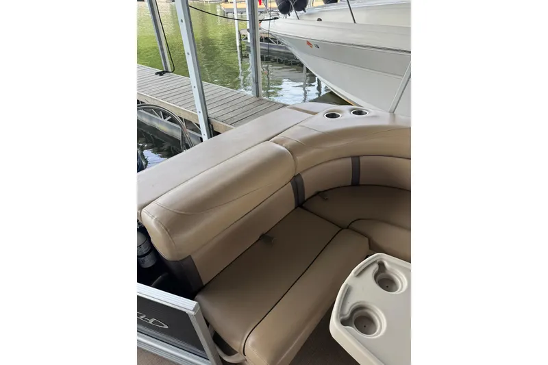 Slide: The Image of 2019 Harris CX 230 pontoon boat with beige seating and cup holders at dock. - 9
