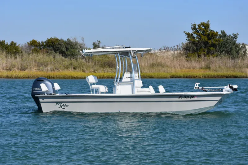 Slide: The Image of 2017 Bay Rider 2260 FS Skiff boat on water, side view, with Yamaha engine. - 2