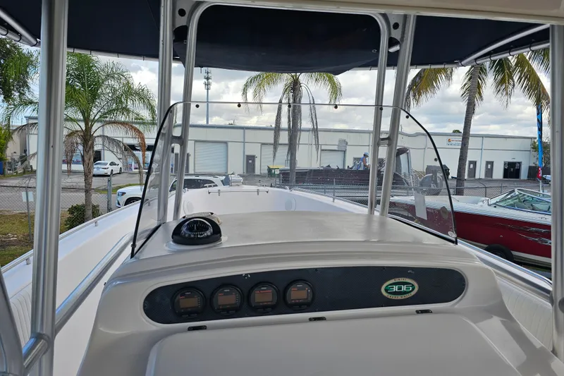 Slide: The Image of 2003 Grady-White Bimini 306 boat dashboard with compass and gauges, palm trees in background. - 24