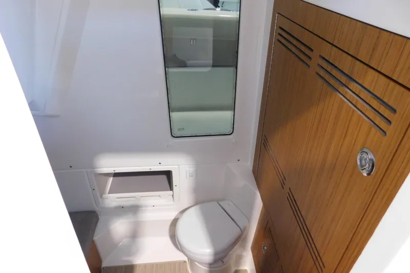 Slide: The Image of 2025 Solace 32 CS boat interior with compact bathroom and wooden cabinetry. - 13