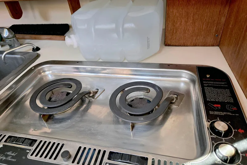 Slide: The Image of 1985 S2 Yachts 9.2 C galley with dual-burner stove and water container. - 15