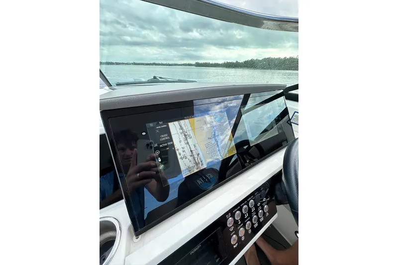 Slide: The Image of 2022 Sea Ray SLX 350 Outboard dashboard with navigation display on a calm water backdrop. - 13