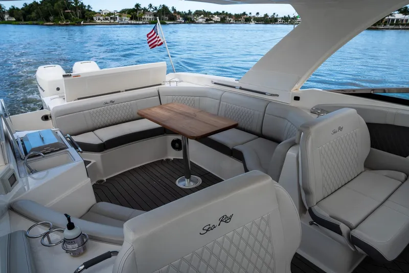 Slide: The Image of 2022 Sea Ray SLX 350 Outboard interior with luxurious seating and wooden table on water. - 2