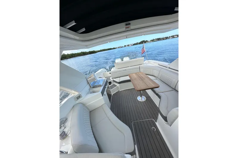 Slide: The Image of 2022 Sea Ray SLX 350 Outboard interior with elegant seating and wooden table on open water. - 23