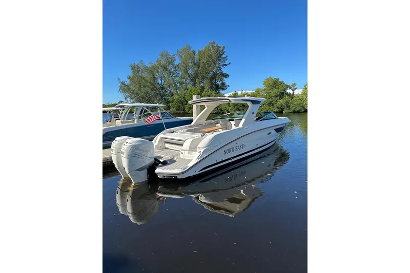 Slide: The Image of 2022 Sea Ray SLX 350 Outboard boat docked on calm water, clear blue sky. - 28