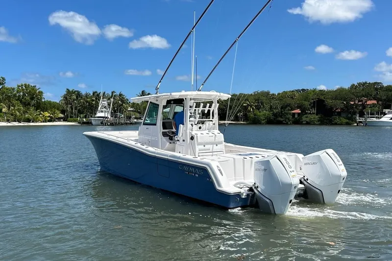 Slide: The Image of 2024 Caymas 30 CT boat cruising on a sunny day with twin Mercury engines. - 2