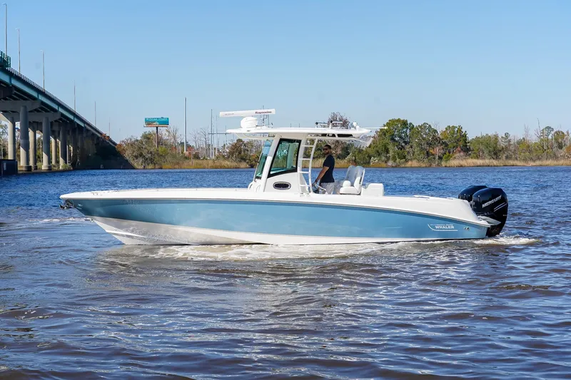Slide: The Image of 2013 Boston Whaler 320 Outrage boat cruising on a river near a bridge. - 10