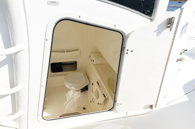 Slide: The Image of 2013 Boston Whaler 320 Outrage boat interior with open door to compact bathroom. - 27