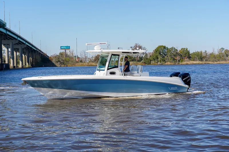 Slide: The Image of 2013 Boston Whaler 320 Outrage boat cruising on a river near a bridge. - 9