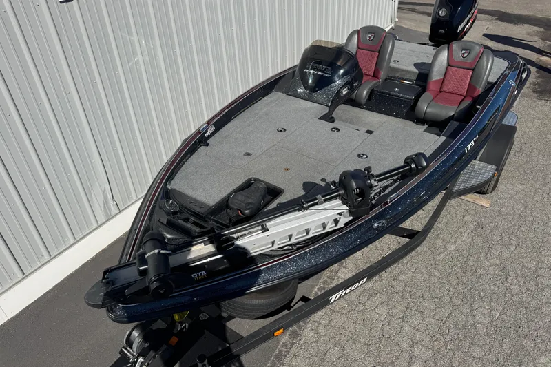 Slide: The Image of 2016 Triton 179 TrX fishing boat with dual seats and trolling motor, parked outdoors. - 3