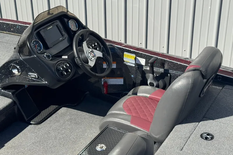 Slide: The Image of 2016 Triton 179 TrX boat cockpit with steering wheel, dashboard, and cushioned seat. - 7