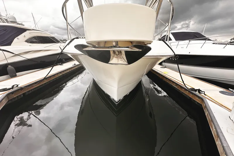 Slide: The Image of 2004 McKinna 57 PHMY Widebody yacht docked, reflecting on calm water under cloudy skies. - 27