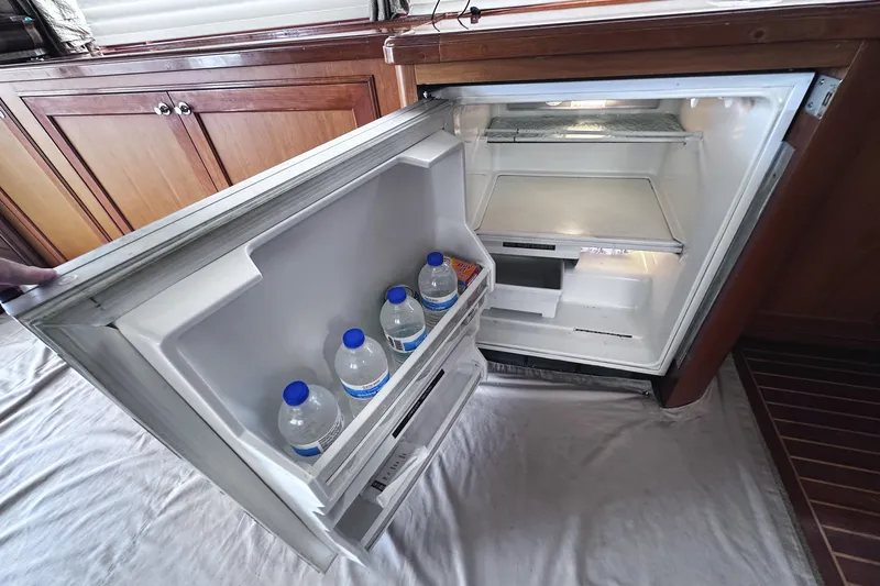 Slide: The Image of Open fridge on 2004 McKinna 57 PHMY yacht, containing water bottles and a snack. - 44