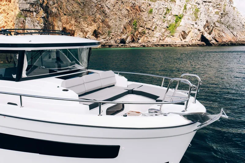 Slide: The Image of 2026 Jeanneau NC895 Sport boat near rocky shoreline. - 6