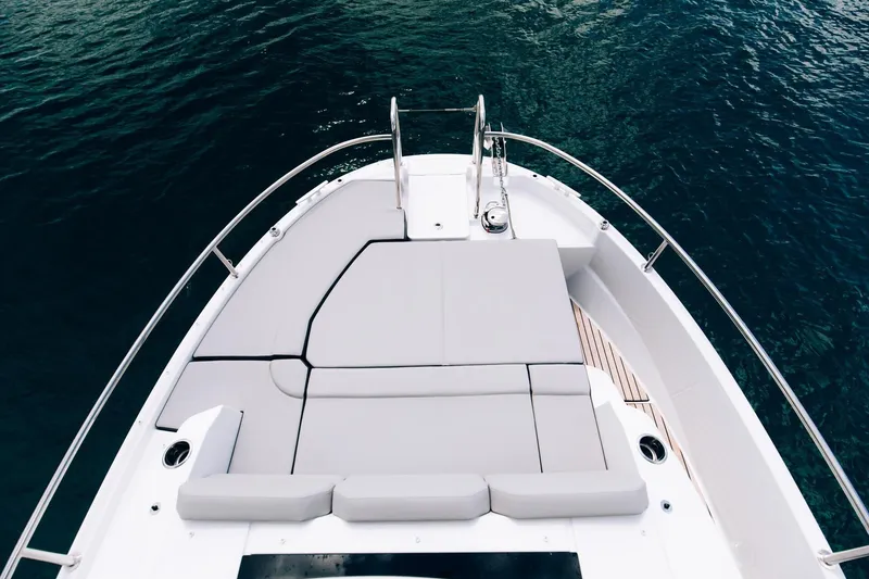 Slide: The Image of 2026 Jeanneau NC895 Sport boat deck with cushioned seating, overlooking calm blue water. - 14