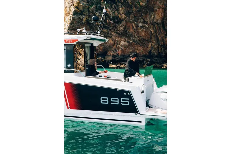 Slide: The Image of 2026 Jeanneau NC895 Sport boat on turquoise water near rocky cliffs. - 8