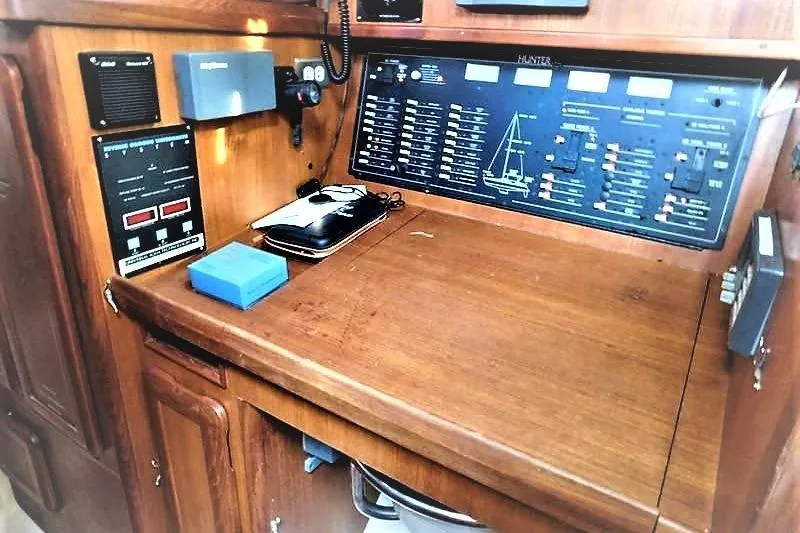 Slide: The Image of 1994 Hunter Passage 42 yacht navigation station with control panel and wooden desk. - 10