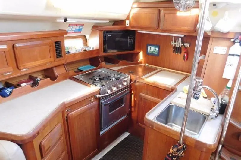 Slide: The Image of 1994 Hunter Passage 42 yacht kitchen with stove, sink, and wooden cabinetry. - 12