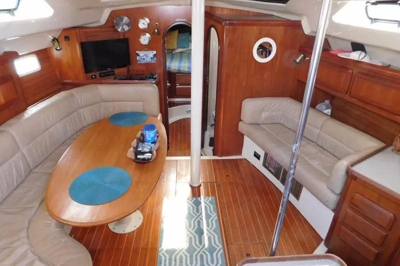 Slide: The Image of 1994 Hunter Passage 42 yacht interior with wood finish, cozy seating, and nautical decor. - 16