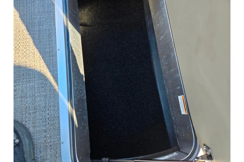 Slide: The Image of Storage compartment of 2021 Barletta C24UC pontoon boat, featuring black interior lining. - 20