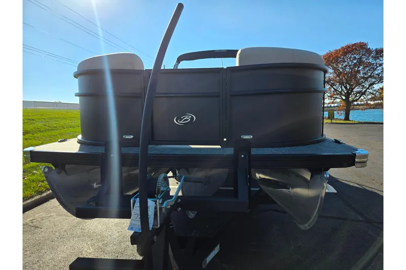 Slide: The Image of 2021 Barletta C24UC pontoon boat on trailer, parked near a lake under clear blue sky. - 7