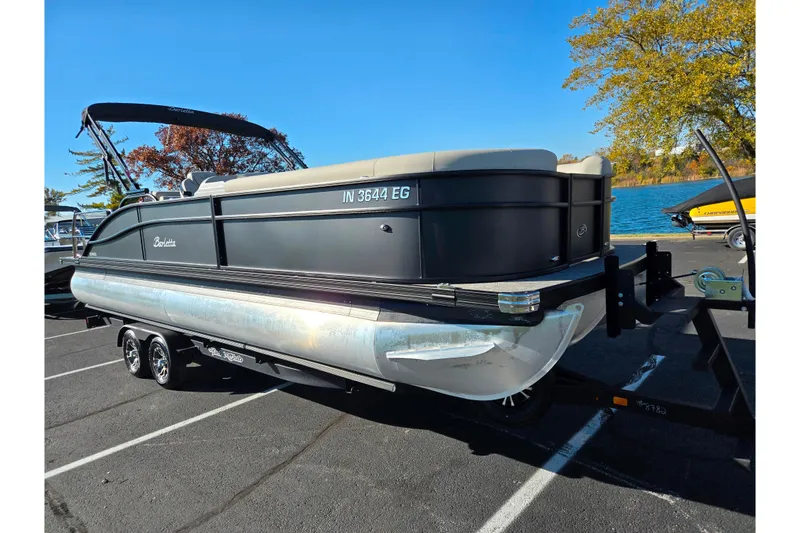 Slide: The Image of 2021 Barletta C24UC pontoon boat on trailer, parked near a lake. - 9
