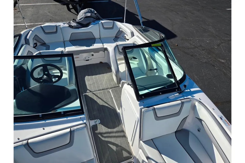 Slide: The Image of 2018 Yamaha Boats SX190 interior with seating and steering wheel, docked on pavement. - 19