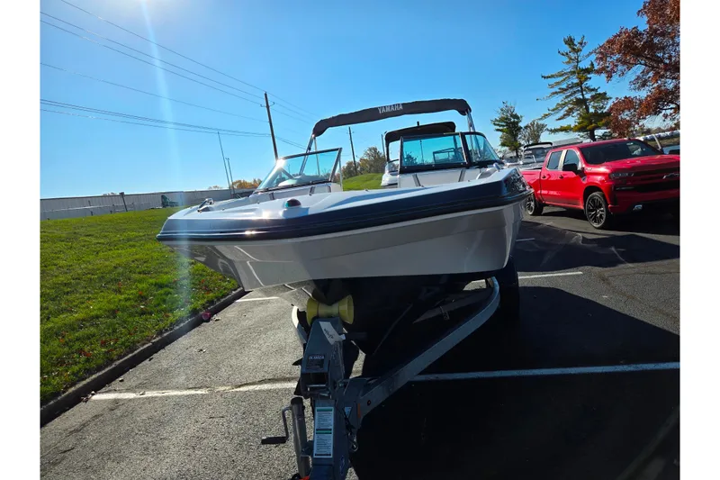 Slide: The Image of 2018 Yamaha Boats SX190 on trailer, parked beside a red truck, under clear blue sky. - 6