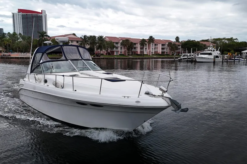 Slide: The Image of 1999 Sea Ray 340 boat cruising near waterfront buildings and palm trees. - 14