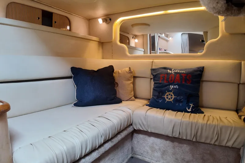 Slide: The Image of Interior of 1999 Sea Ray 340 boat with cozy seating and nautical-themed pillows. - 17