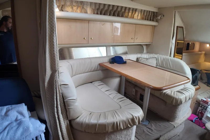 Slide: The Image of 1999 Sea Ray 340 cabin interior with dining area and beige seating. - 23