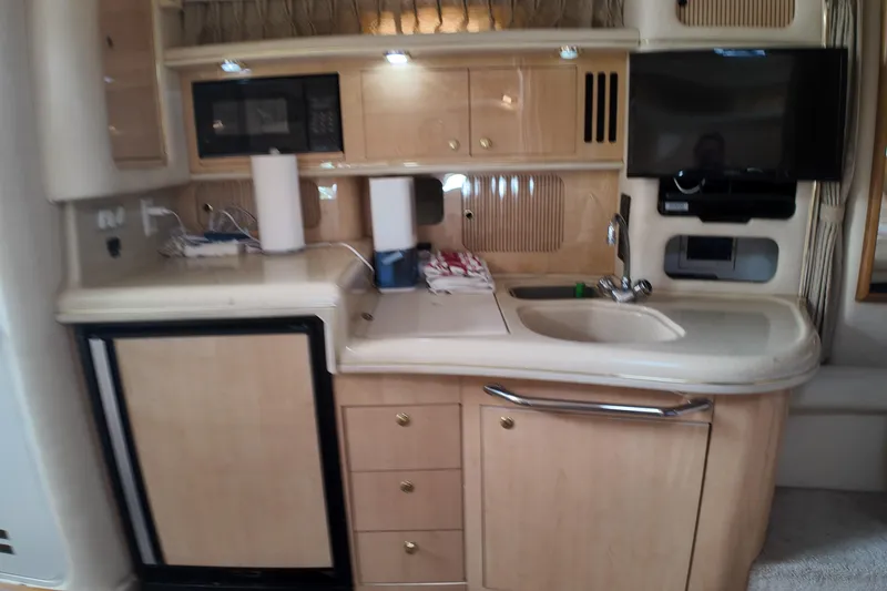 Slide: The Image of 1999 Sea Ray 340 yacht interior kitchen with sink, cabinets, and appliances. - 24
