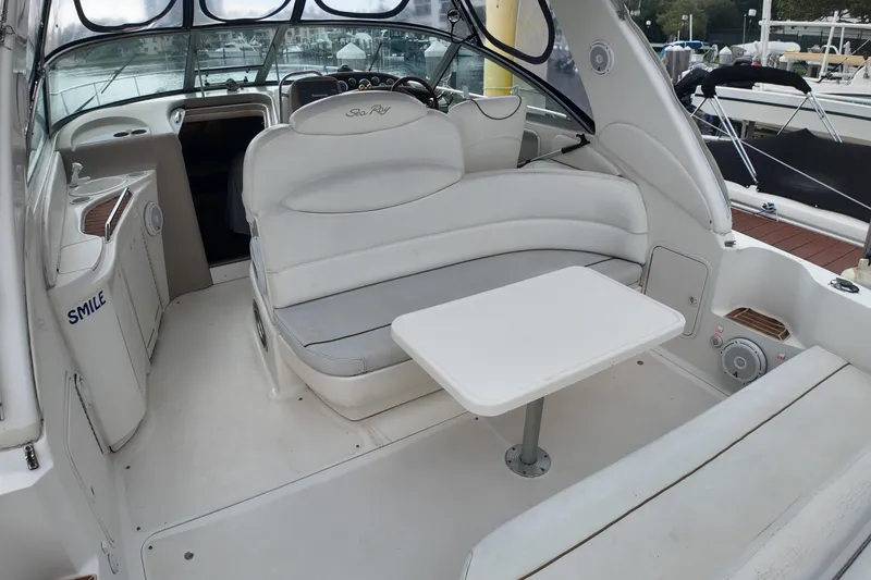 Slide: The Image of 1999 Sea Ray 340 boat interior with white seating and table, docked at marina. - 27