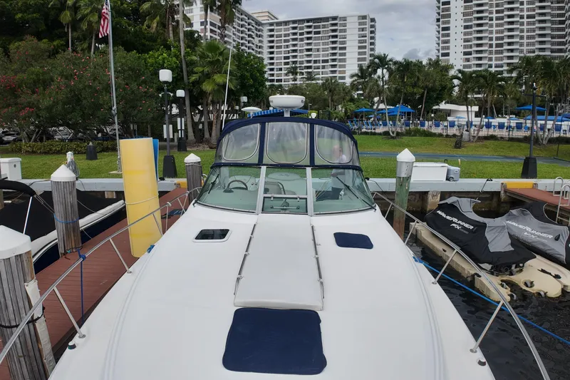 Slide: The Image of 1999 Sea Ray 340 yacht docked at marina with lush greenery and buildings in background. - 35