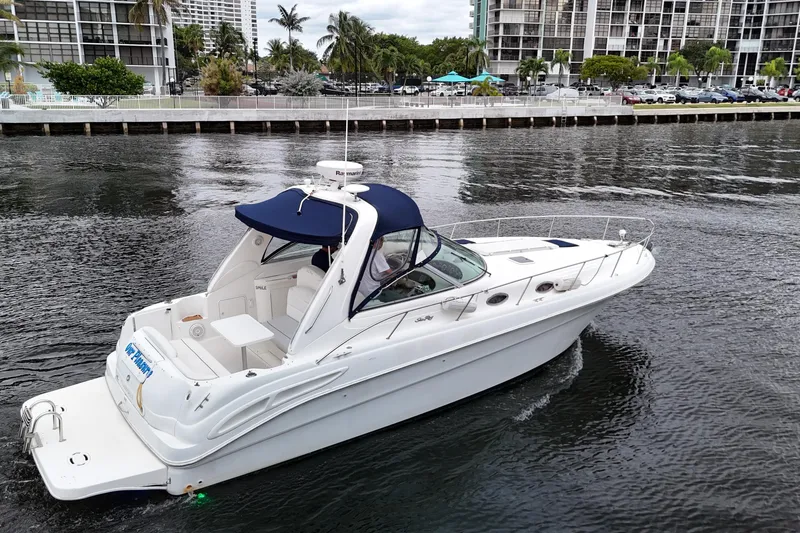 Slide: The Image of 1999 Sea Ray 340 boat cruising on a calm waterway near urban buildings. - 4