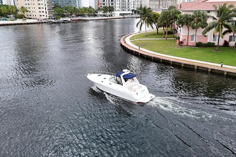 Slide: The Image of 1999 Sea Ray 340 cruising in a scenic waterfront area with palm trees and buildings. - 8