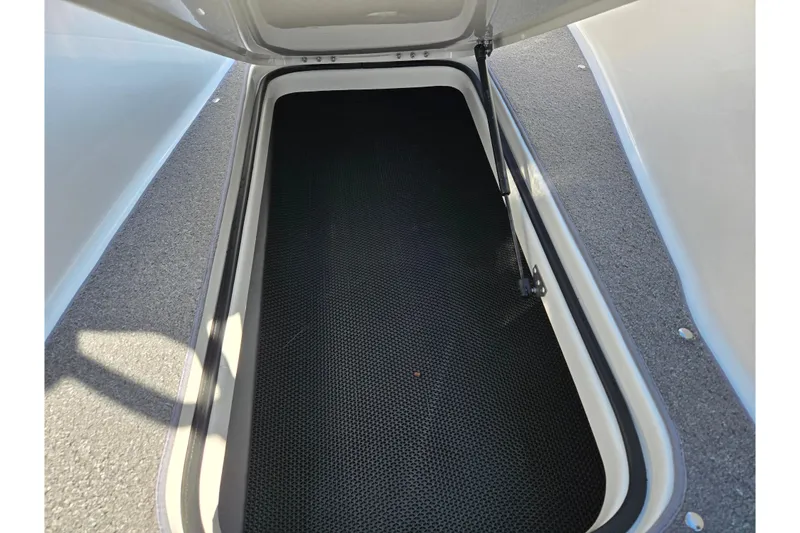 Slide: The Image of Open storage compartment in 2011 Bayliner 197 boat, featuring black mat and gray carpet. - 14