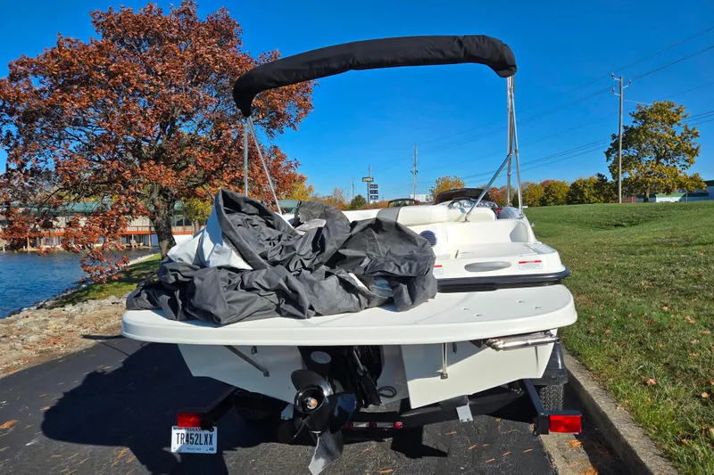 Slide: The Image of 2011 Bayliner 197 boat parked near a lake with autumn trees in the background. - 2