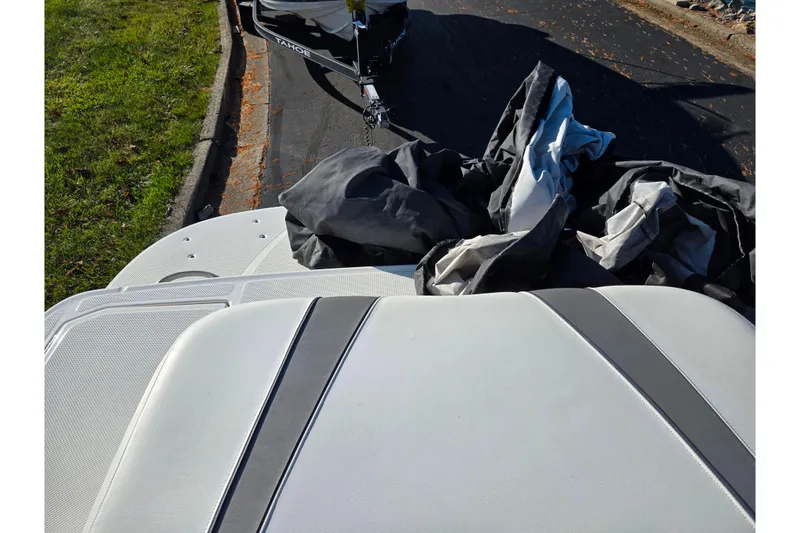 Slide: The Image of 2011 Bayliner 197 boat with cover, parked on street near grass. - 22